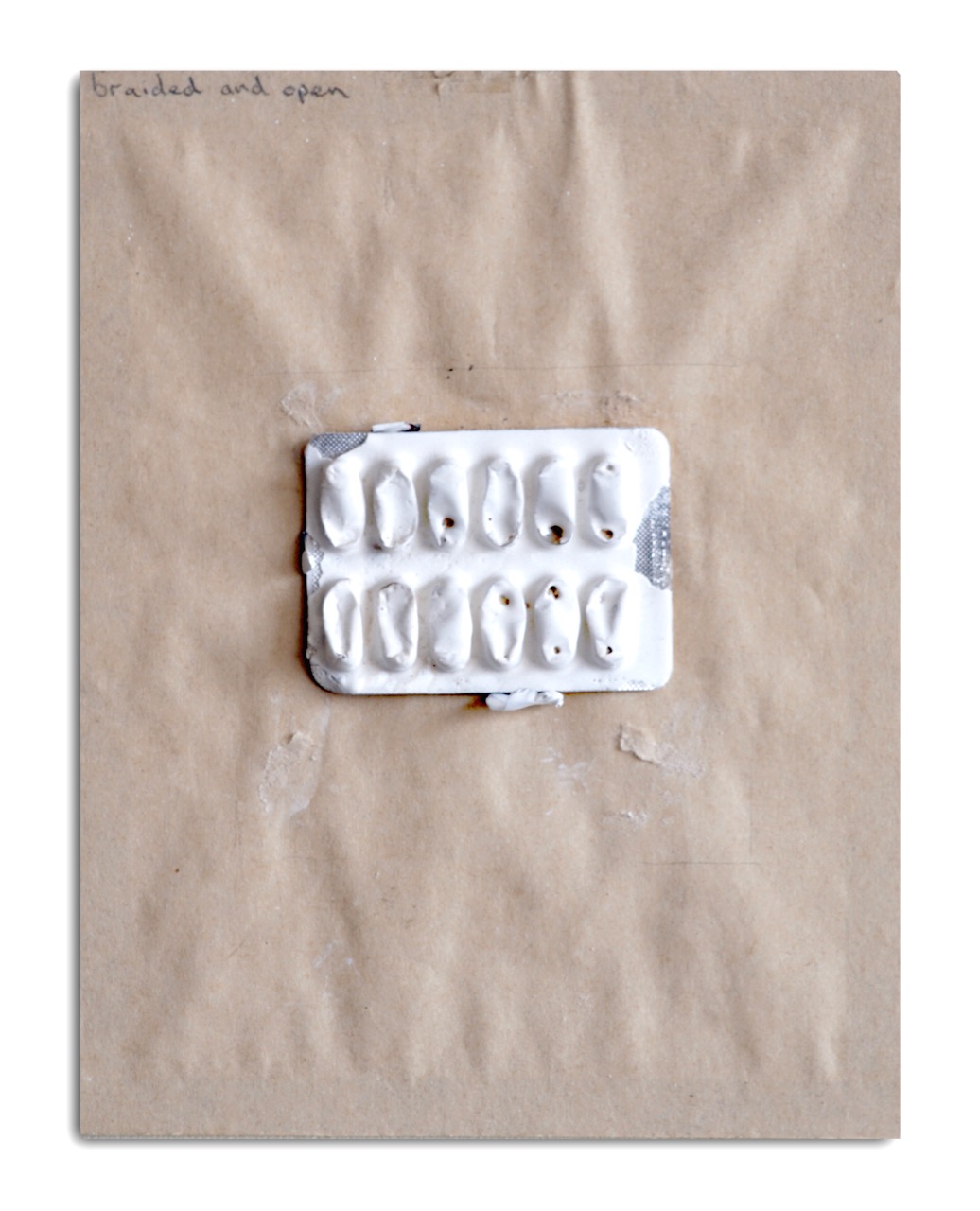 An artistic representation of a pill blister pack, partially opened, placed on a textured brown background. The pack has several empty compartments and appears to be made from a white material.